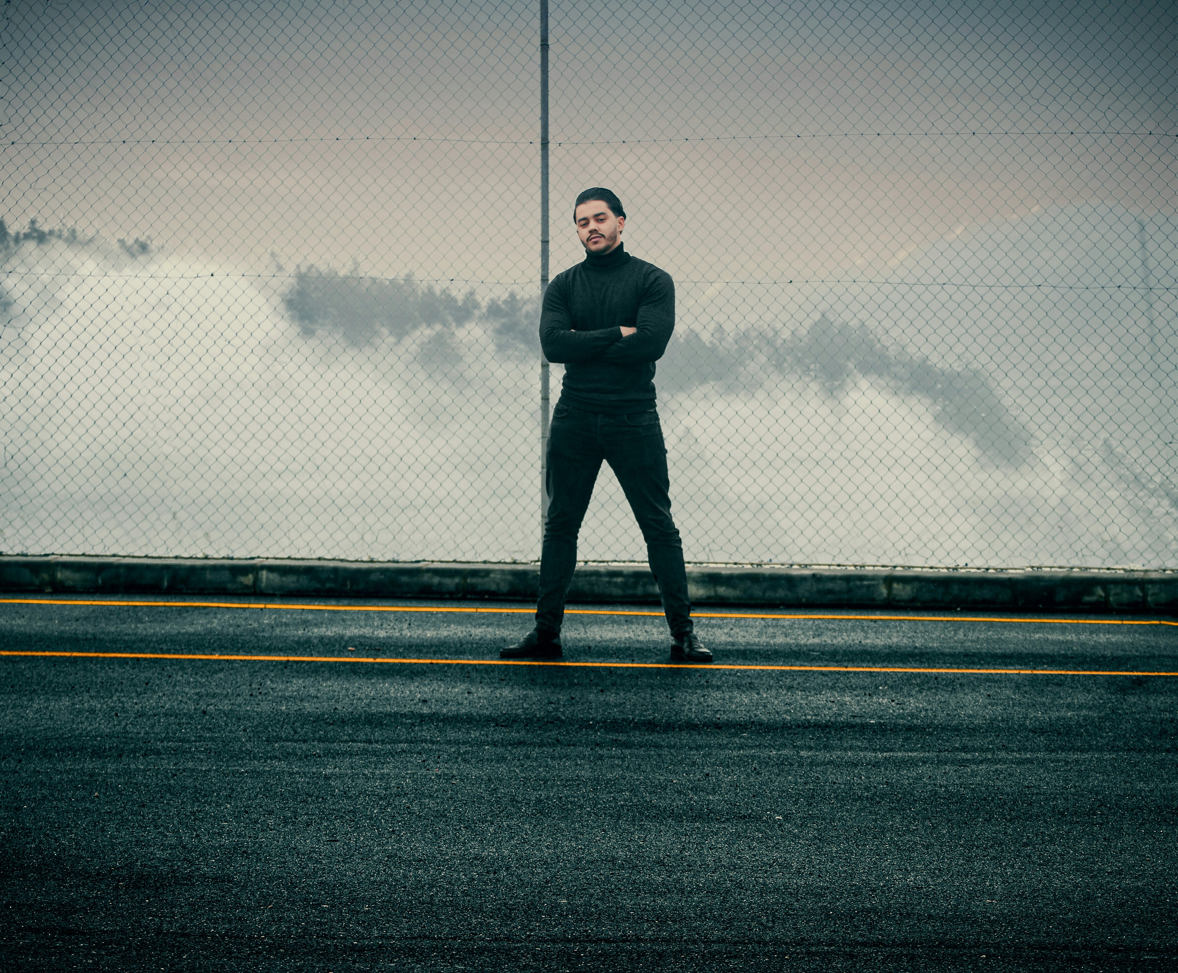 man in black jacket standing on gray asphalt road during daytime